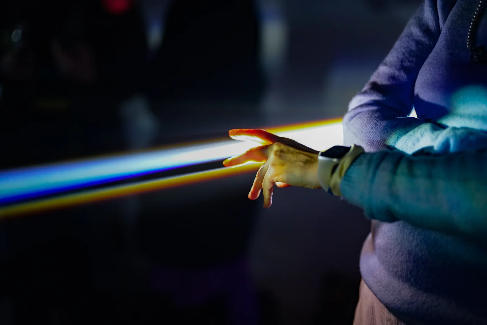 A visitor holds a prism in a beam of light during the Lucid Dream finale.