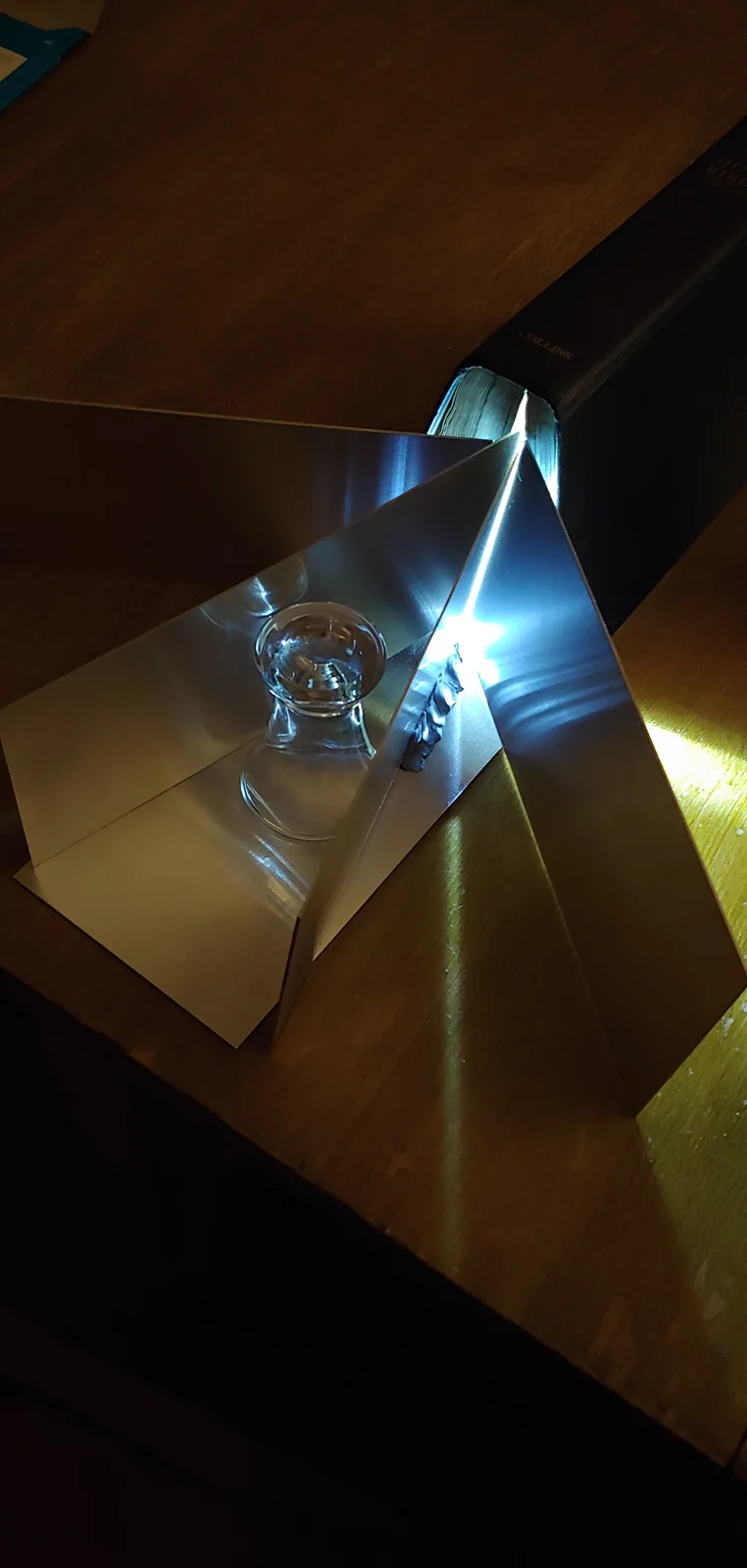 A prism and mirrors on a wooden surface.