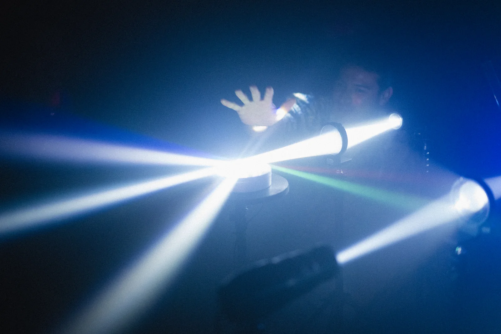 A hand reaches into beams of light.