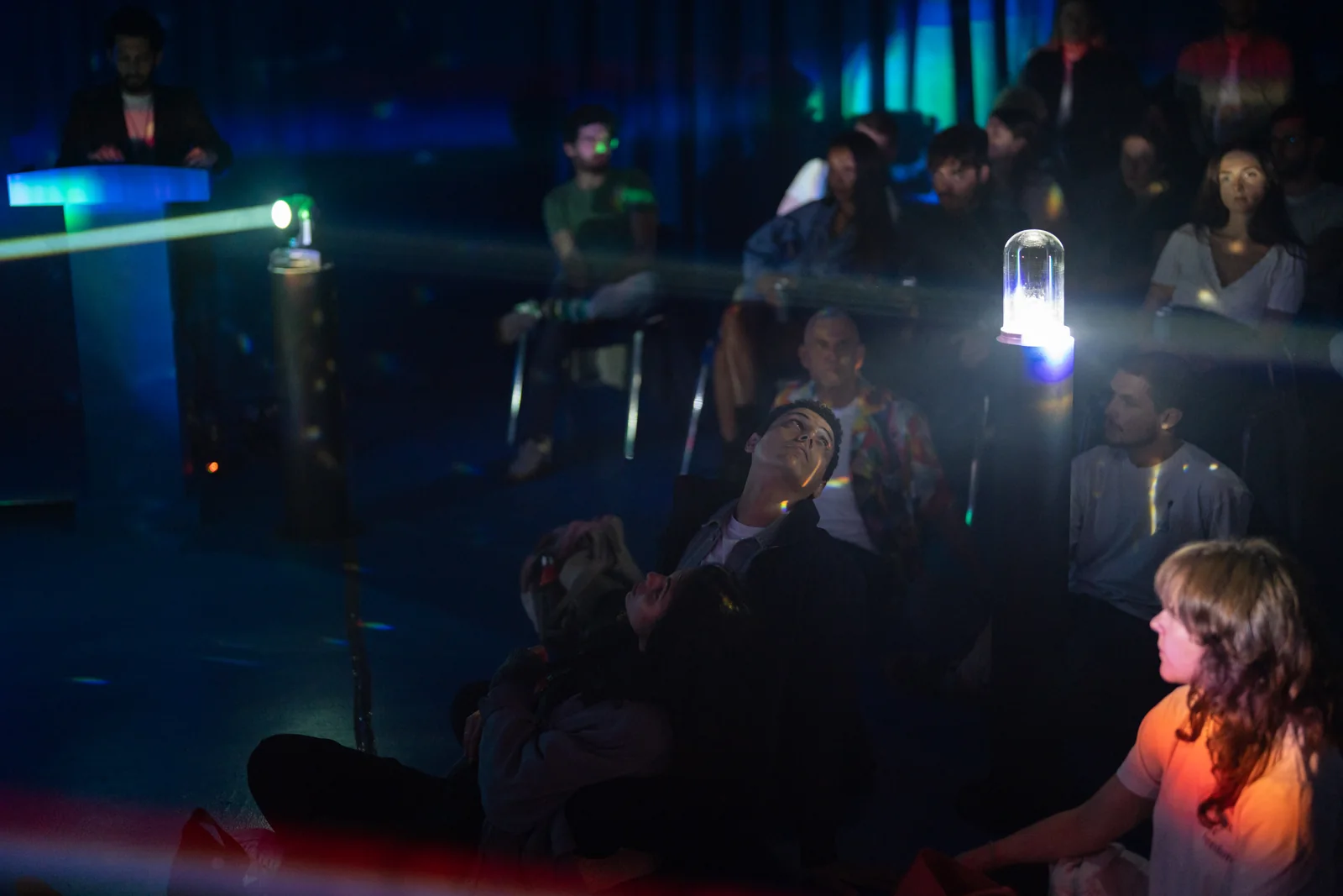 Visitors seated around the beams of light.